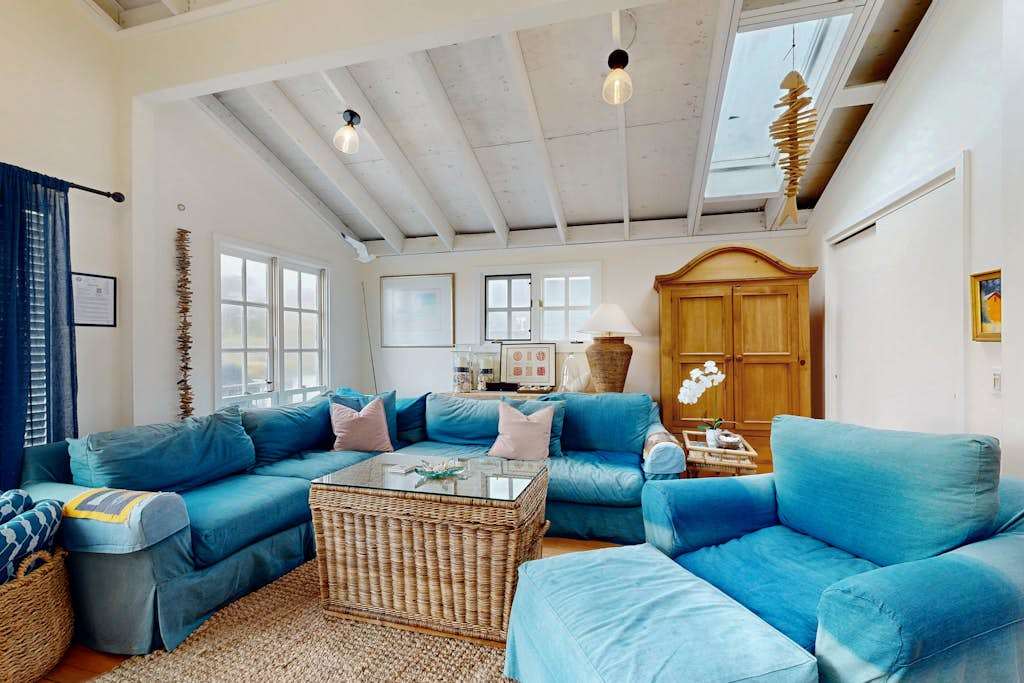 Sink into plush blue sofas beneath vaulted beam ceilings in this sun-drenched Bodega Bay living room — your coastal retreat starts here.