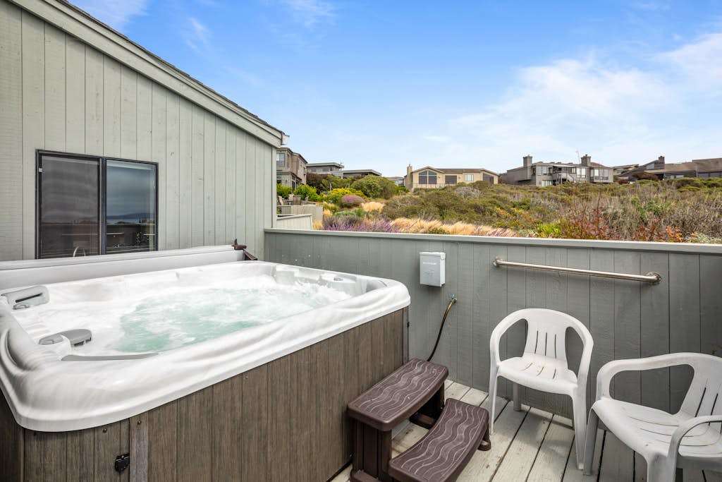 Bubbling and ready, your private hot tub sits on a sunny upper deck with views across the coastal neighborhood.