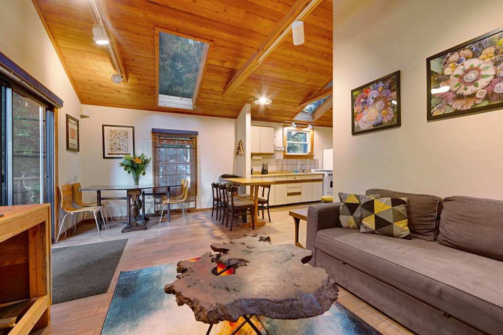 Gather in the open-plan living area where vaulted wood ceilings, eclectic art, and a live-edge coffee table set a warm wine country tone.