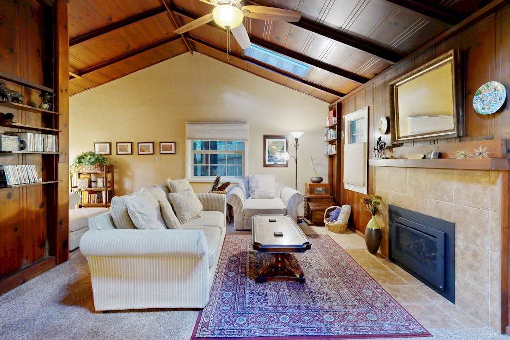 Gather around the gas fireplace in this vaulted-ceiling living room with skylights, plush sofas, and a curated book collection.
