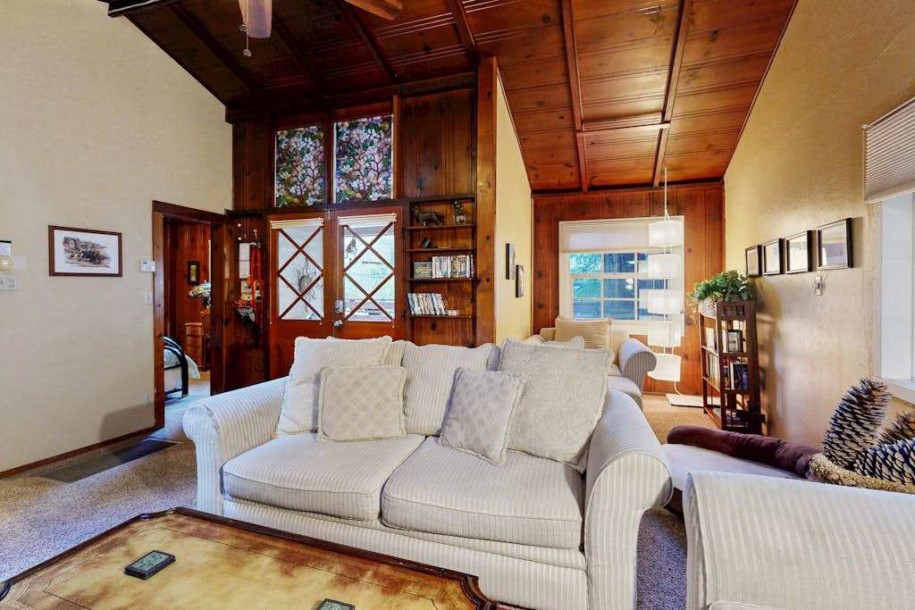 Charming wood-paneled walls and a glass-front bookcase give your living space a warm, cabin-inspired redwood retreat feel.