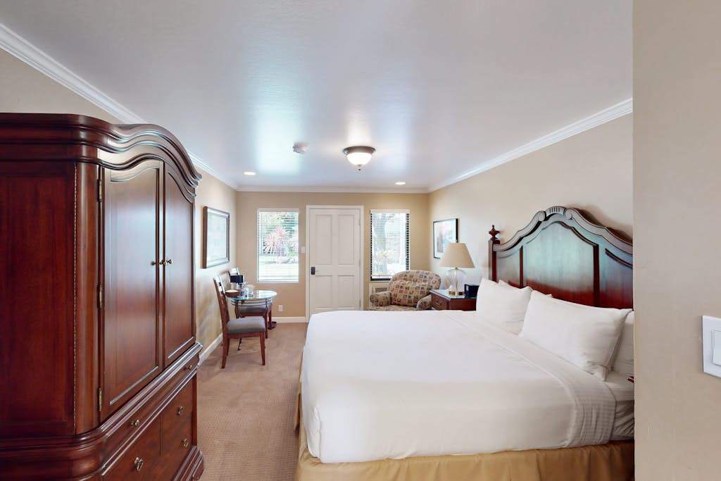 Rest easy in your spacious king bedroom featuring a stately armoire, elegant furnishings, and soft carpeting throughout