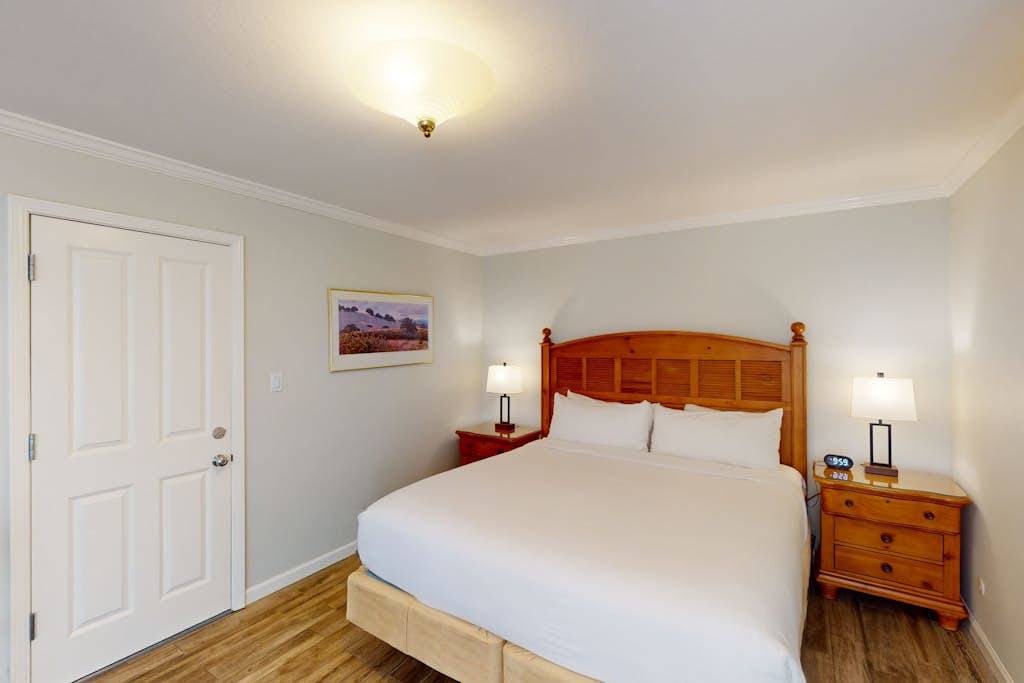 Sink into your plush king bed after a day exploring Napa Valley wineries — crisp white linens and warm wood furnishings set a restful wine country tone.