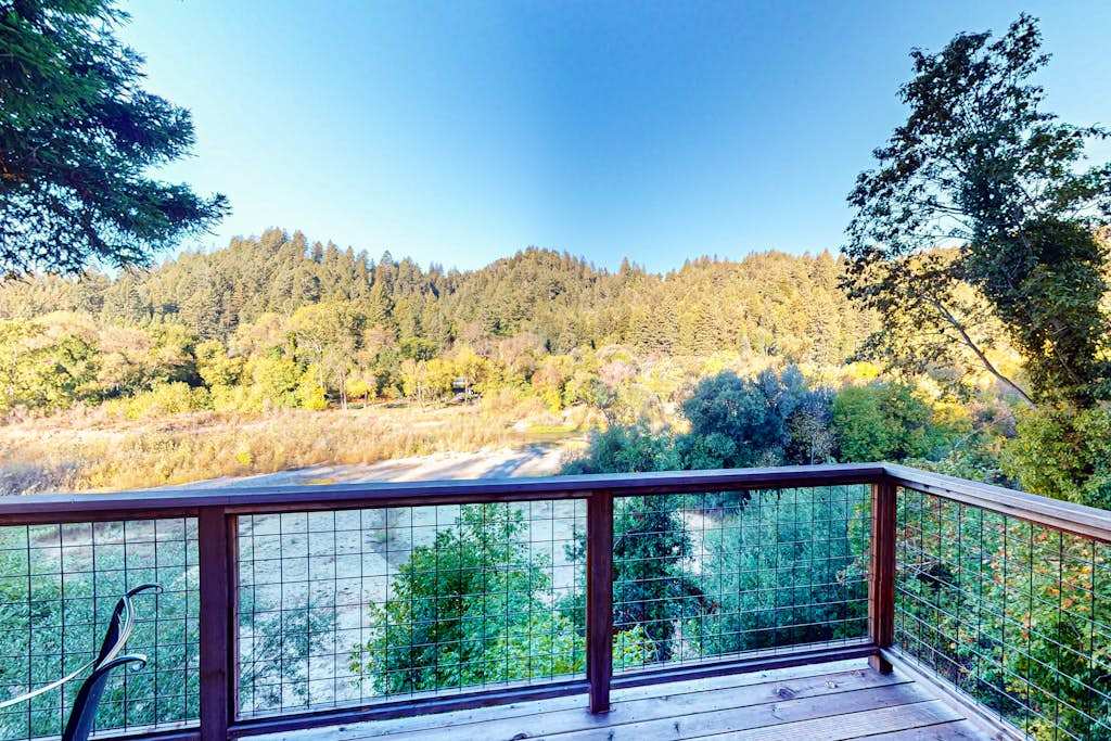 Lean into the cable railing and let the river valley panorama steal your breath — forested ridgelines and the shimmering Russian River below your deck.