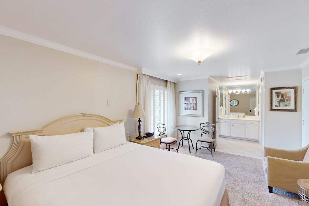 Settle into your elegantly appointed Napa Valley suite featuring a plush king bed, bistro seating area, and soft natural light — your wine country sanctuary awaits.