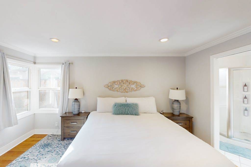 Matching nightstands and soft lighting frame your king bed for cozy evenings — step through the doorway to freshen up in your private en-suite bath
