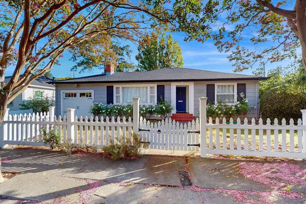 Welcome to your wine country hideaway — a charming cottage with white picket fence, flower boxes, and a private entrance tucked beneath mature shade trees in Santa Rosa