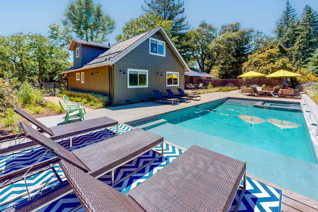 Dive into your Sonoma wine country escape — a sparkling private pool flanked by striped loungers awaits after a day exploring nearby tasting rooms.