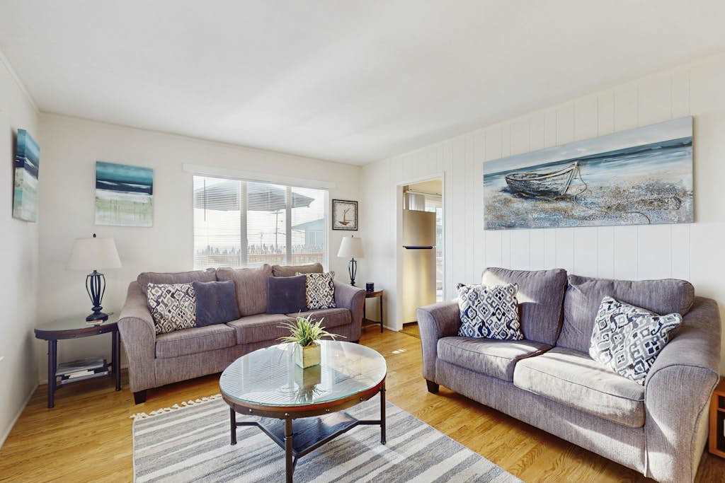 Sink into plush coastal-chic sofas surrounded by ocean-inspired artwork in your sunlit Bodega Bay living room — the perfect spot to unwind after a day exploring the Sonoma Coast.