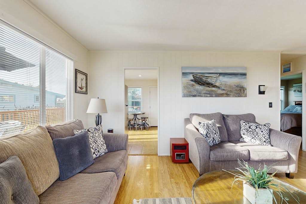 Let natural light pour through sliding glass doors as you relax among coastal artwork and warm hardwood floors — your gateway to the deck is just steps away.