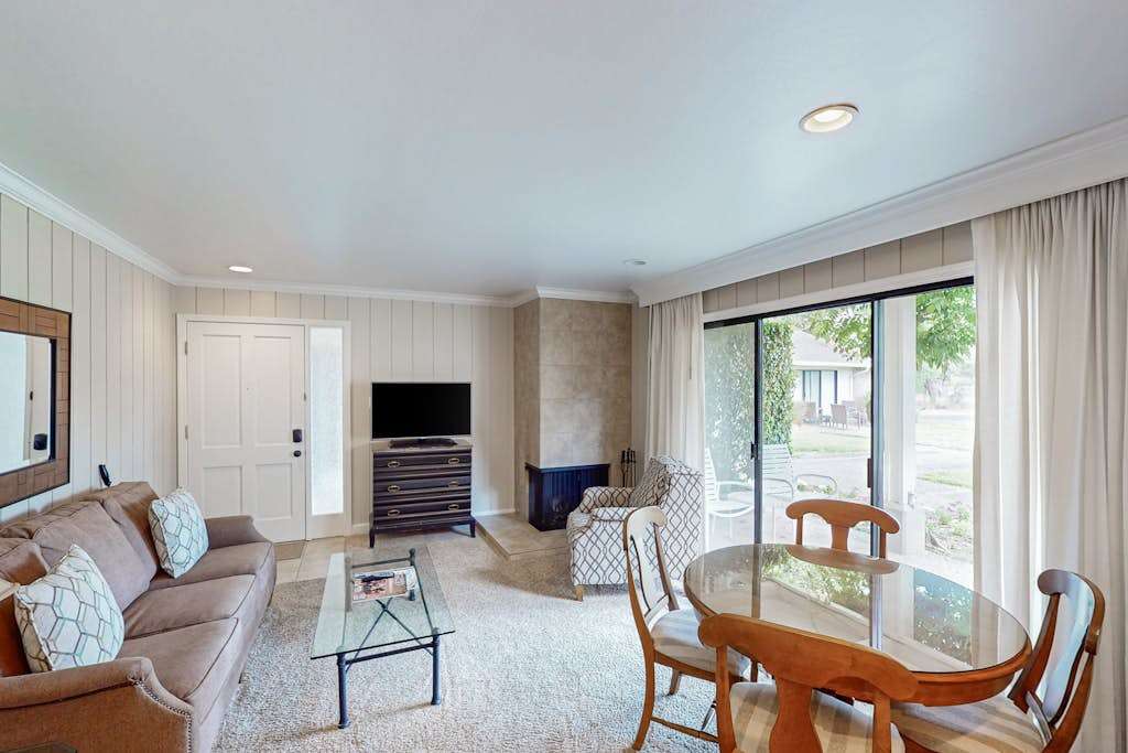 Gather around the fireplace in your spacious Napa condo living room with a flat-screen TV, comfortable seating, and natural light from floor-to-ceiling glass doors