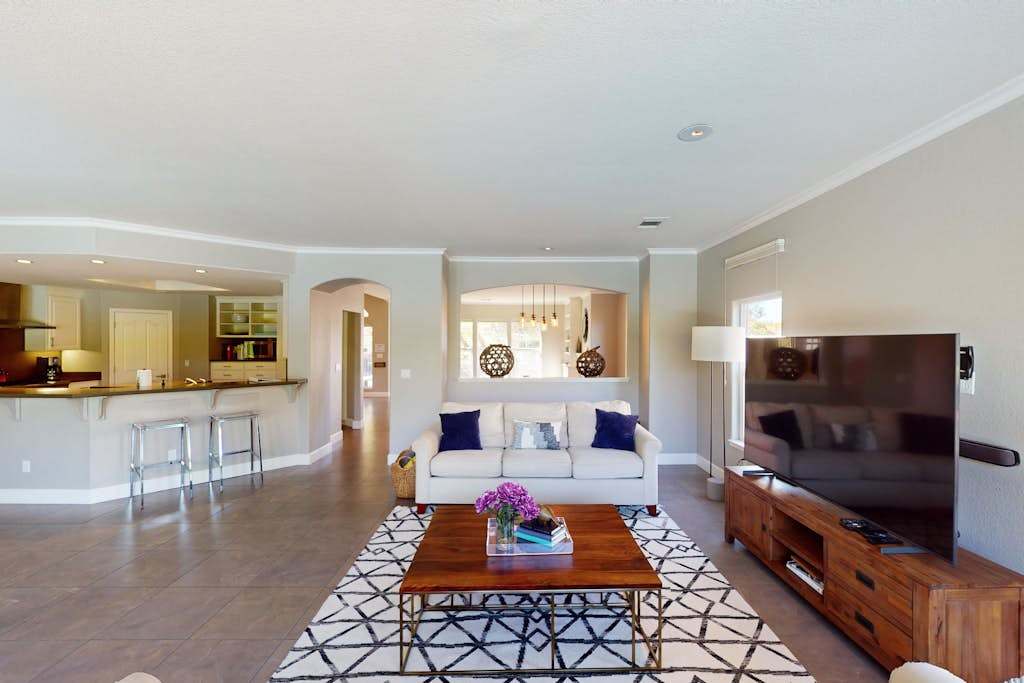 Stretch out in your sun-drenched open-concept living room with a large flat-screen TV, designer furnishings, and a kitchen pass-through ideal for entertaining.