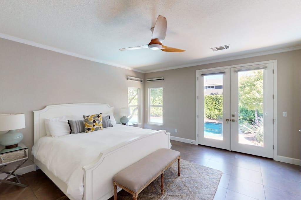 Wake in the luxurious king-suite with a modern ceiling fan, poolside french doors, and crisp white linens — your Sonoma wine country sanctuary.