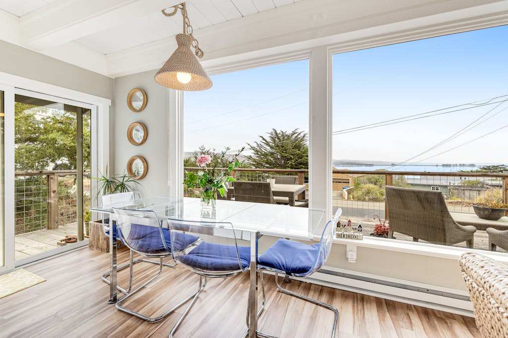 Savor morning coffee at your sunlit dining table with panoramic views of Bodega Harbor — glass walls blur the line between indoors and the bay beyond.