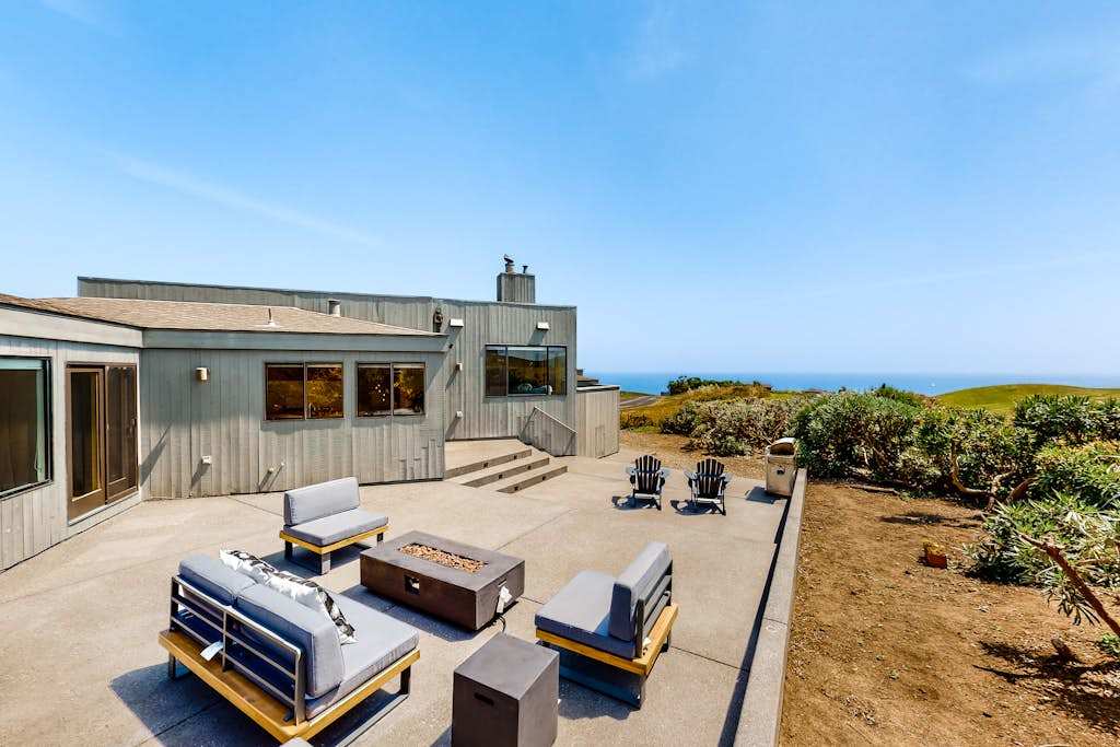 Unwind on your expansive private patio with plush lounge seating, Adirondack chairs, and a fire pit framed by sweeping Pacific Ocean views