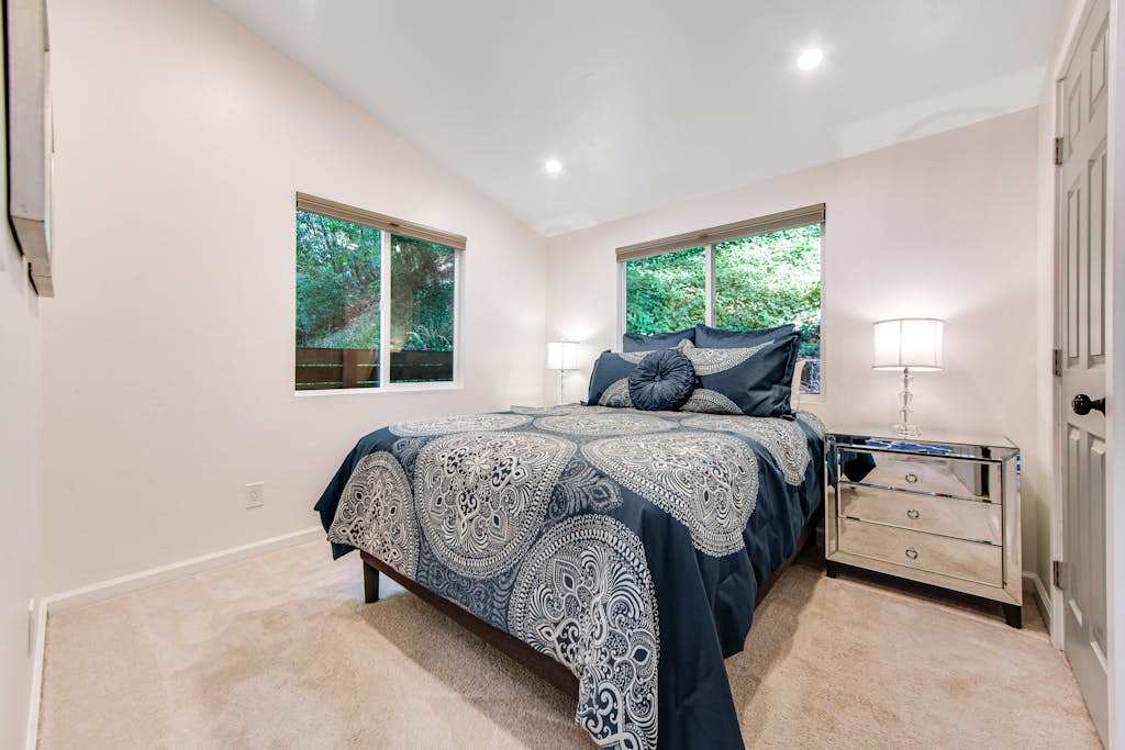 Drift off in your tranquil main-floor bedroom — a plush queen bed draped in designer linens with windows that frame nothing but lush redwood greenery.