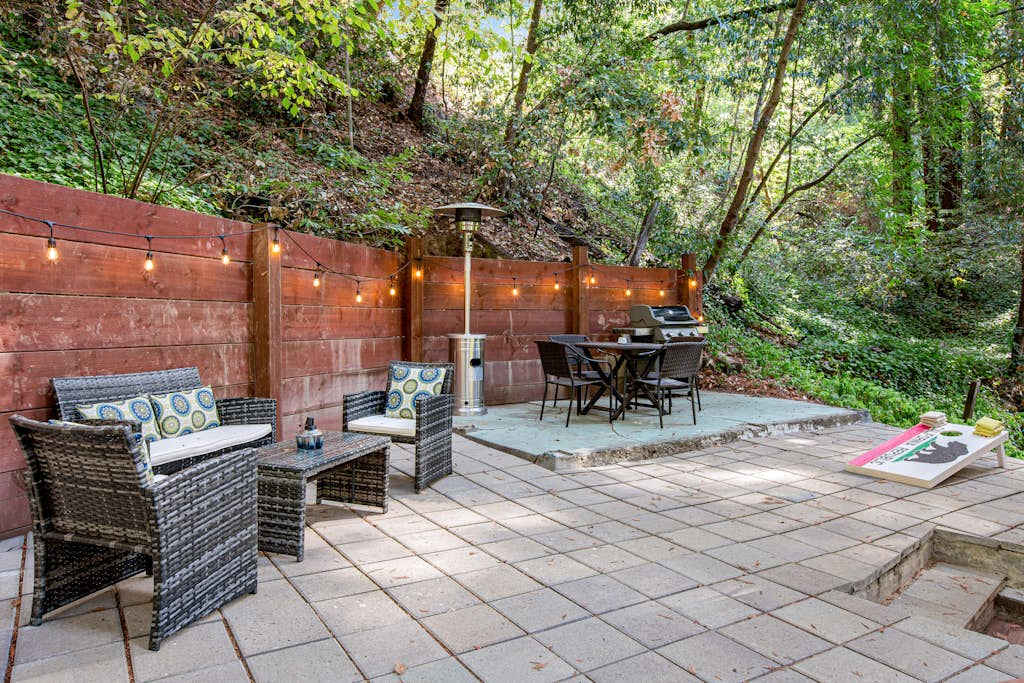 Unwind beneath twinkling string lights on your private patio — lounge seating, outdoor dining, and a cornhole board nestled among towering Guerneville redwoods.