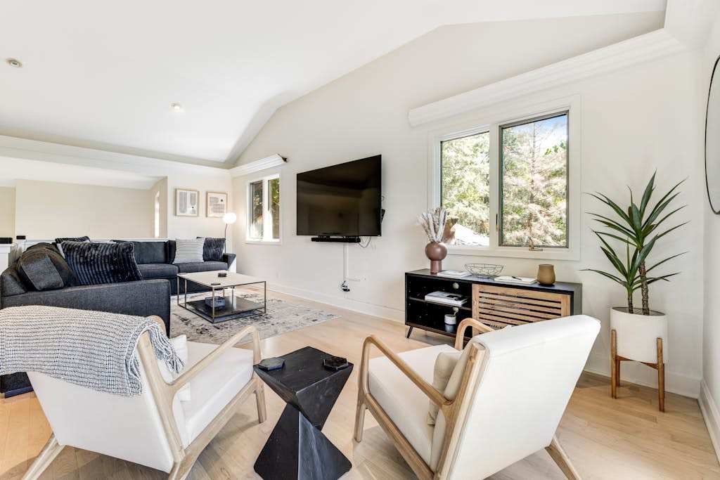 Bright and airy, your main living space welcomes you with modern furnishings, a wall-mounted TV, and sun-drenched windows framing the Sonoma County hillside.