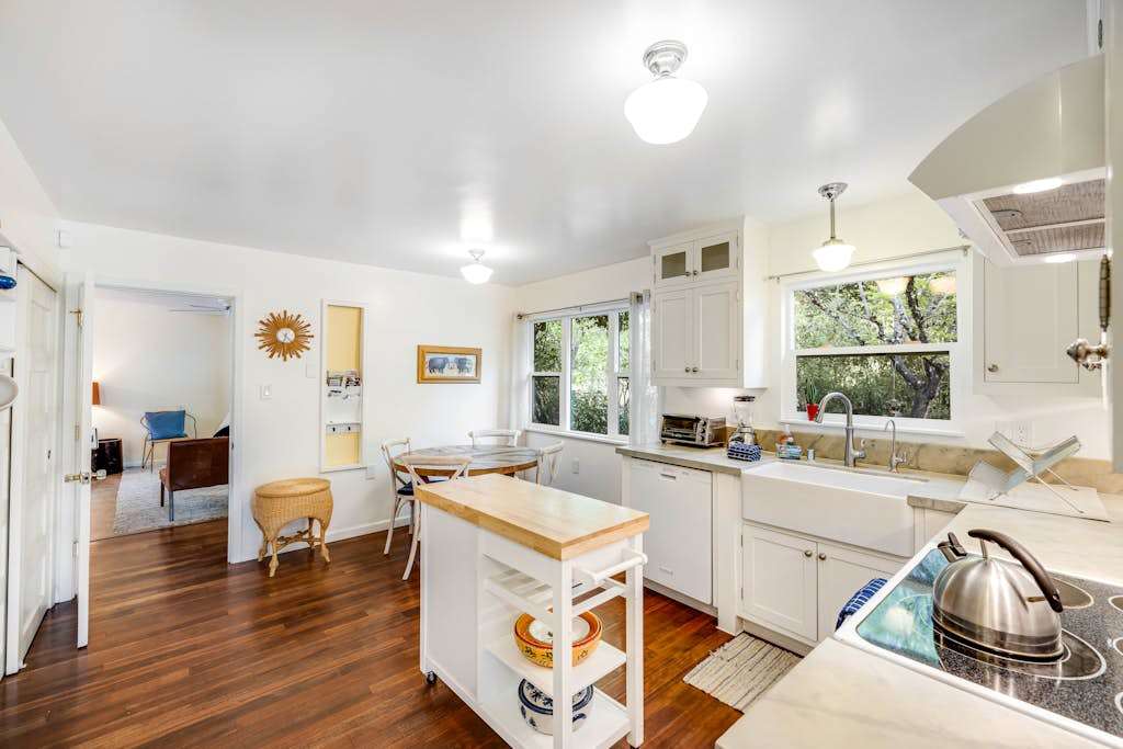 Cook with ease in your bright farmhouse kitchen featuring white cabinetry, a classic apron-front sink, and a handy rolling island