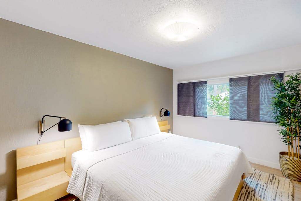 Rest deeply in your second king suite — a calming sage accent wall, modern reading lamps, and lush greenery bring the serenity of the redwoods right to your bedside.
