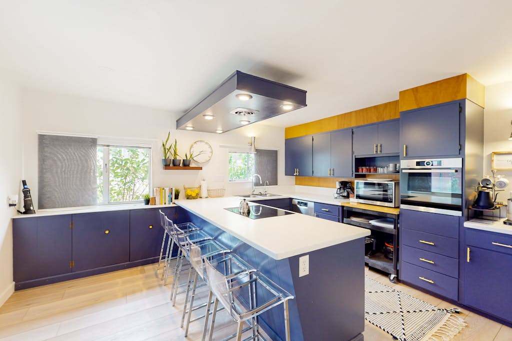 Channel your inner chef in a bold designer kitchen — sleek navy cabinetry, white quartz countertops, and a spacious island with bar seating make cooking a highlight of your stay.