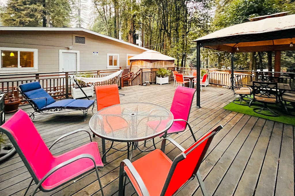 Your deck has room for everyone — hammock naps, lounge-chair reading, and covered dining all unfold under a breathtaking redwood canopy steps from the Russian River.