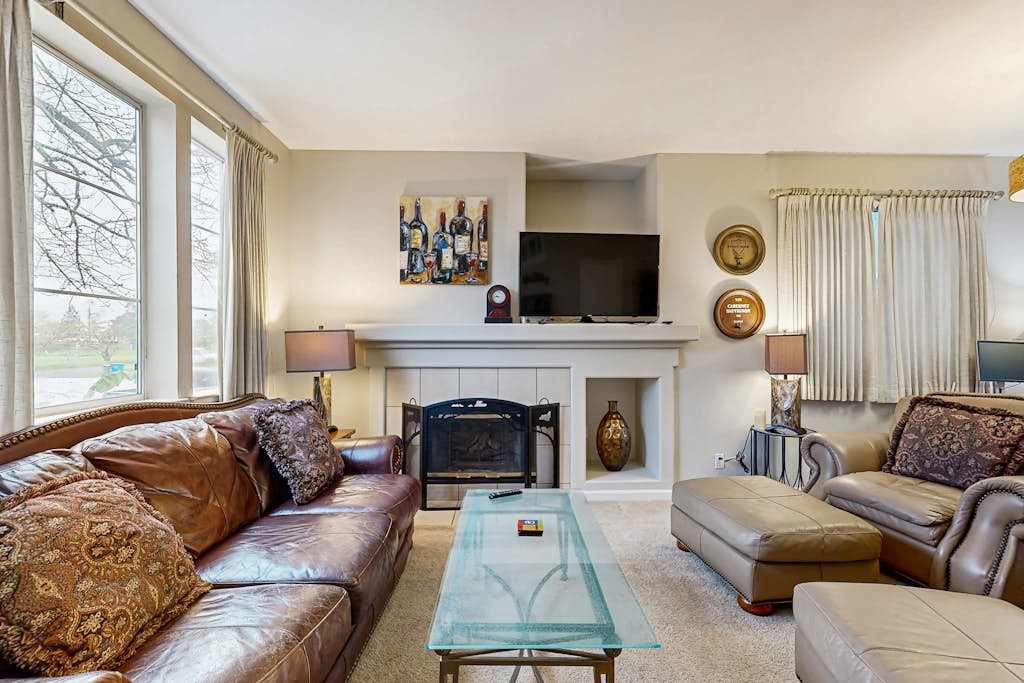 Sink into plush leather seating by the gas fireplace after a day exploring Sonoma vineyards — your living room features a flat-screen TV and warm, curated decor throughout.