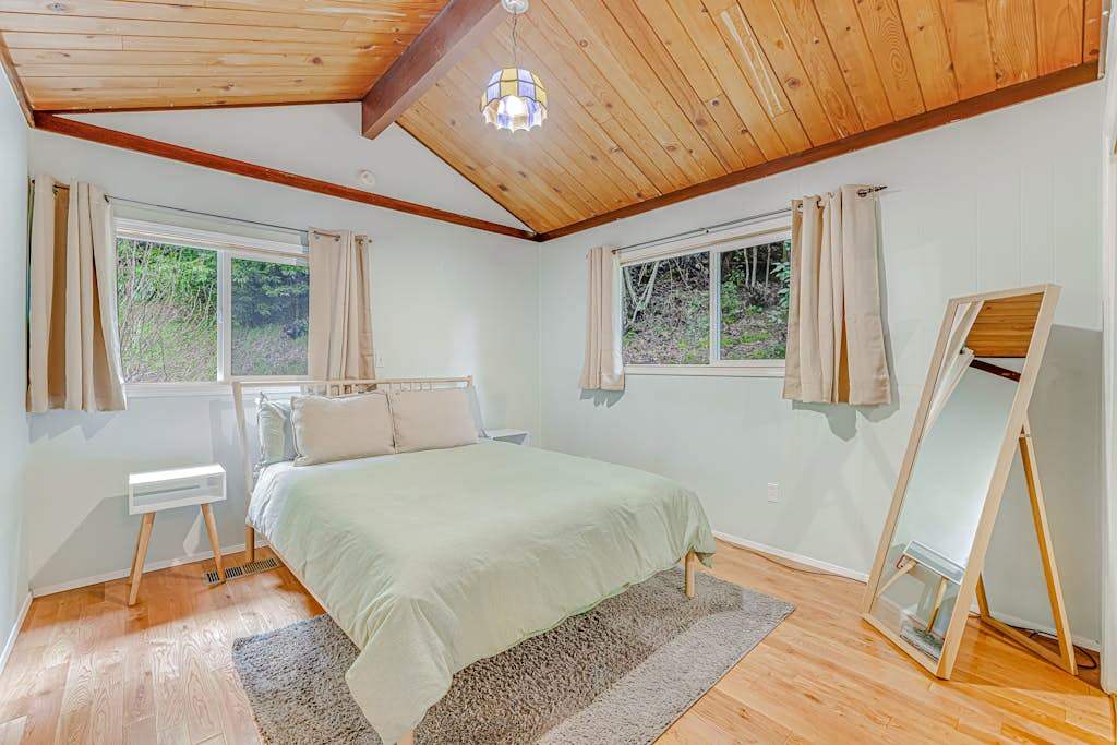 Drift off in your serene primary bedroom — a queen bed, vaulted wood ceiling, and garden-framed windows create the perfect wine country wind-down.