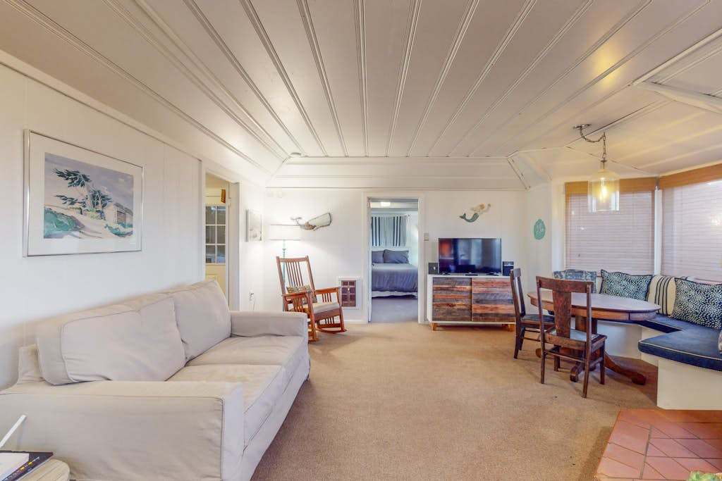 Settle into your sun-filled Bodega Bay living room with plush seating, coastal artwork, and a cozy banquette nook perfect for morning coffee overlooking the Sonoma Coast.