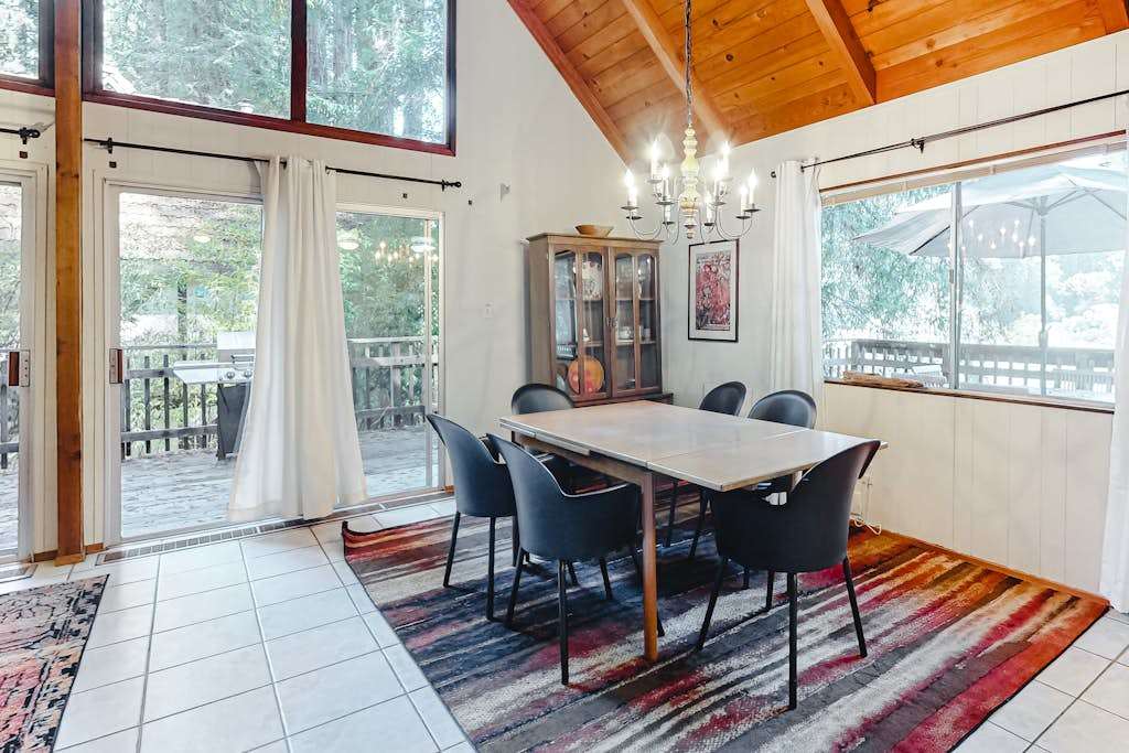 Sunlight streams through panoramic windows onto your dining space — redwood views and elegant touches make every meal feel like a special occasion.
