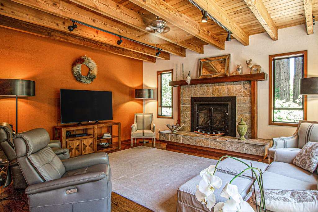 Unwind by the stone-hearth gas fireplace in a vaulted living room with exposed timber beams, a large flat-screen TV, and plush seating for your whole group.