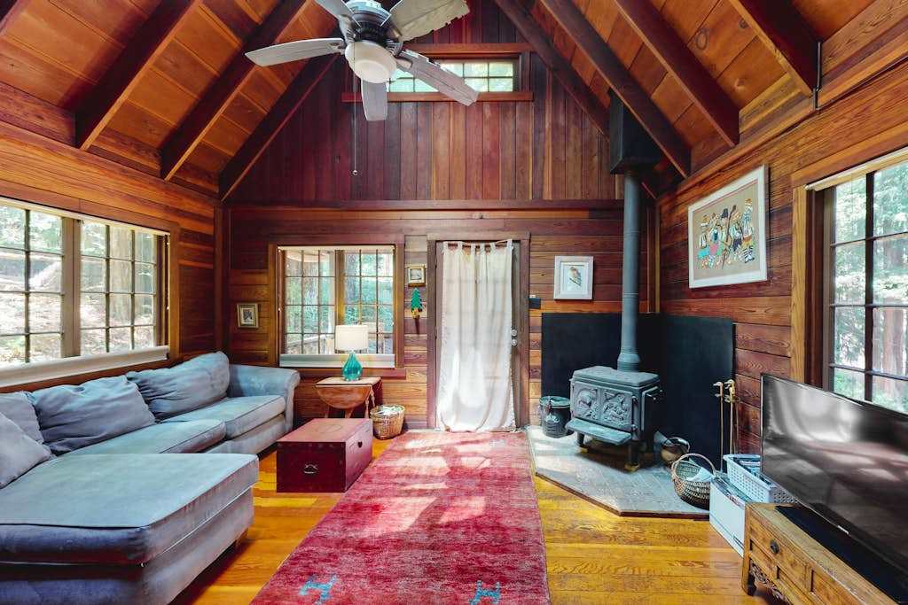 Unwind in your vaulted redwood living room where a cozy gas stove, plush sectional, and warm wood paneling wrap you in true Cazadero cabin comfort.