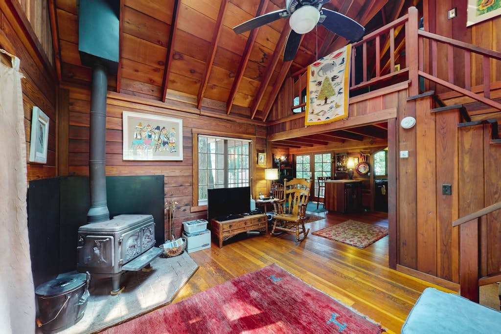 Gather around the stove in your soaring A-frame great room — vaulted redwood ceilings, eclectic art, and a peek at the loft above make every Cazadero evening memorable.