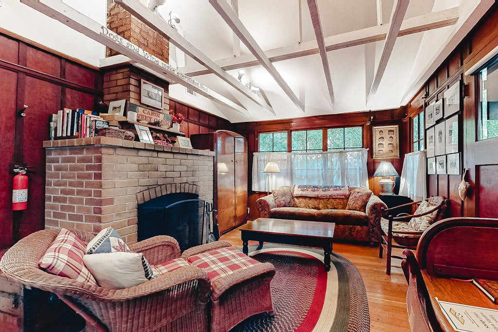 Sink into cozy wicker chairs beside your wood-burning brick fireplace — rich wood paneling and vaulted beams set the tone for a true redwood retreat evening.