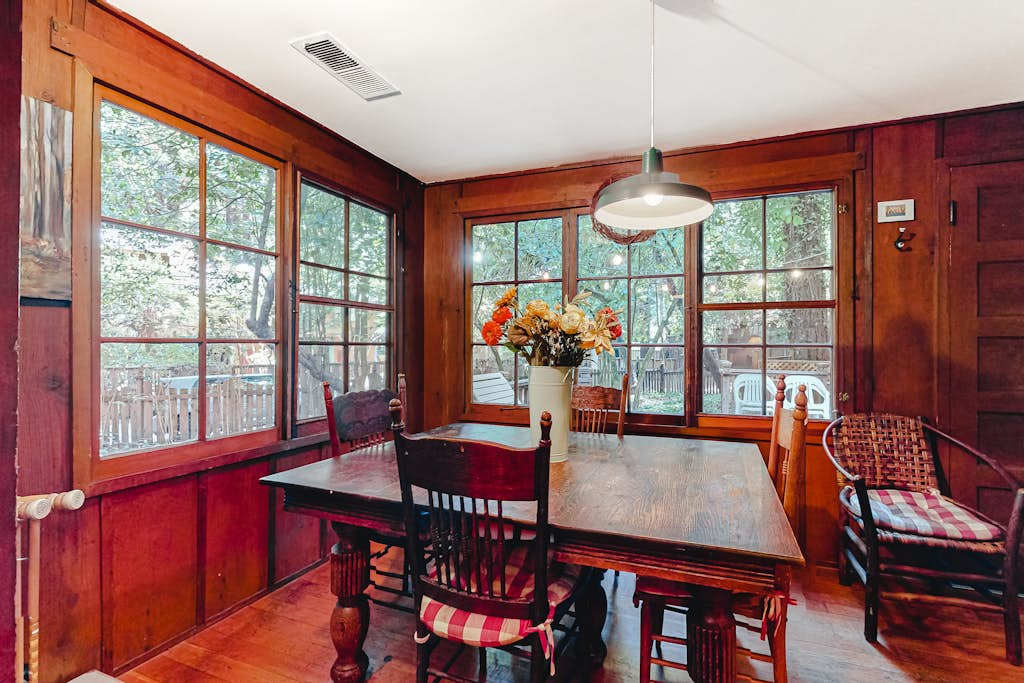 Morning light streams through floor-to-ceiling windows as you enjoy breakfast at your dining table — redwoods and deck just beyond the glass.