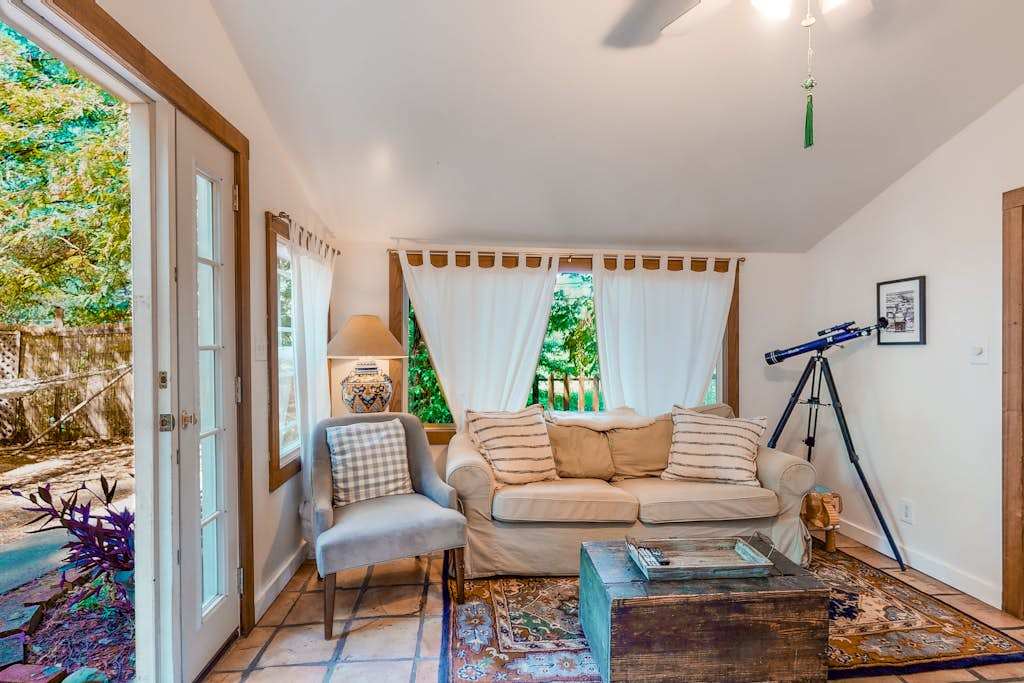 Spot a curious telescope by the window and settle into the cozy sitting area — your cottage living room blends charm with redwood-framed views.