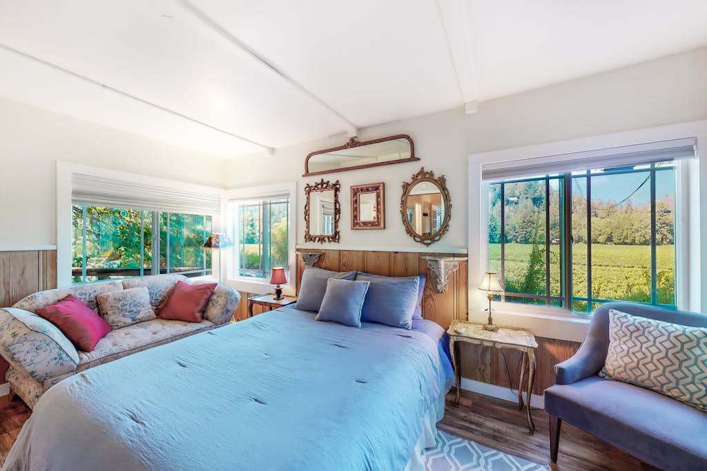 Wake to lush green views in your sunlit master suite — a queen bed, window-side daybed, and vineyard panoramas make this your wine country sanctuary.