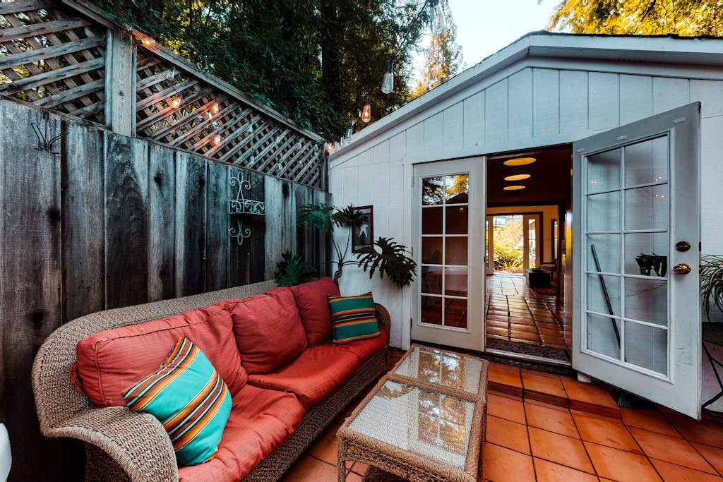 As twilight settles over Guerneville, your cottage glows warmly through open French doors — step between indoor comfort and your private patio retreat.