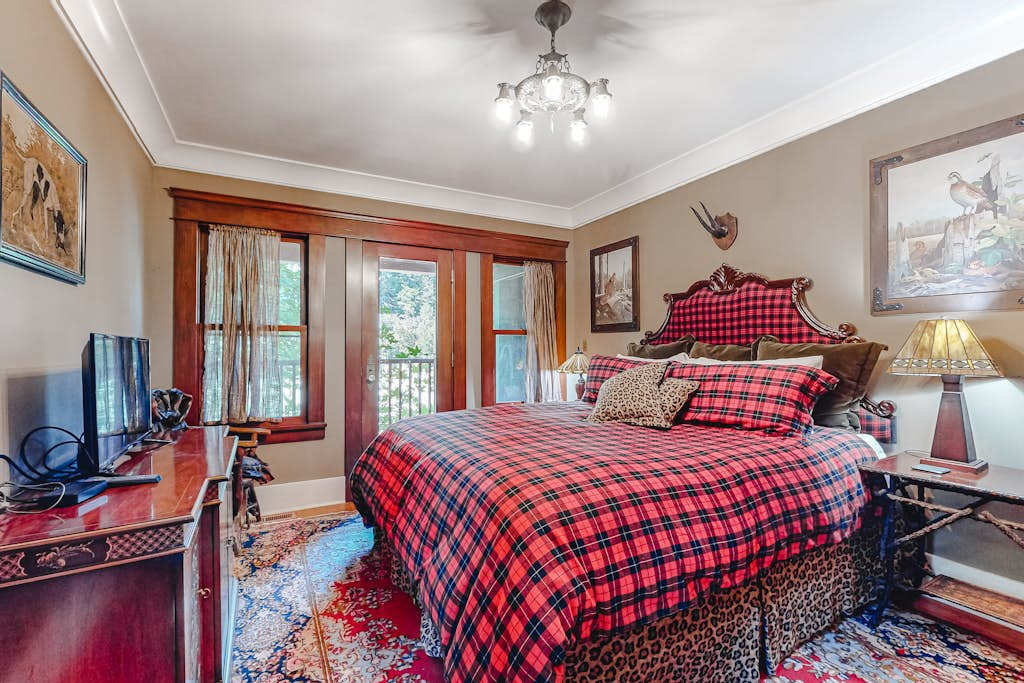 Wake to dappled redwood light in your cozy bedroom — antler accents, a reading lamp, and a TV for winding down after a day exploring Guerneville.
