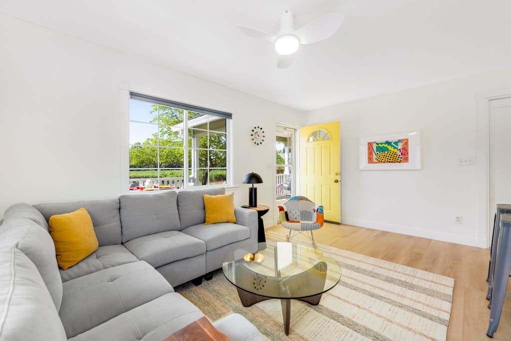 Unwind on the gray sectional with your favorite Dry Creek Valley red — warm light, curated art, and that signature yellow farmhouse door welcoming you home.