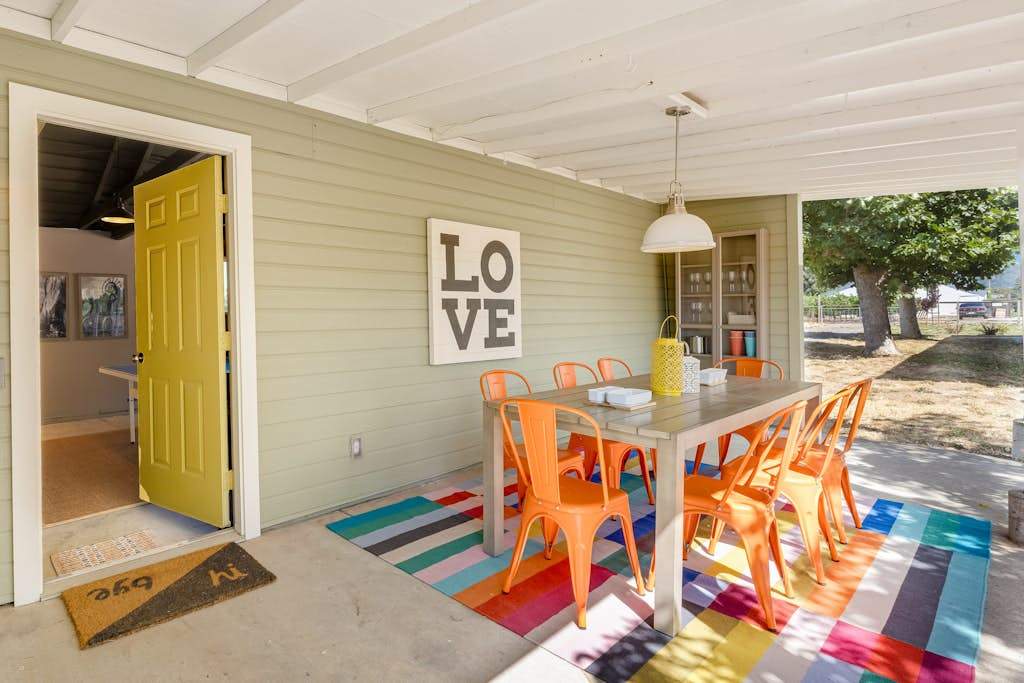 Bright orange chairs and a bold 'LOVE' sign set the tone on your covered patio — grab breakfast at the farmhouse table before your next Healdsburg tasting.