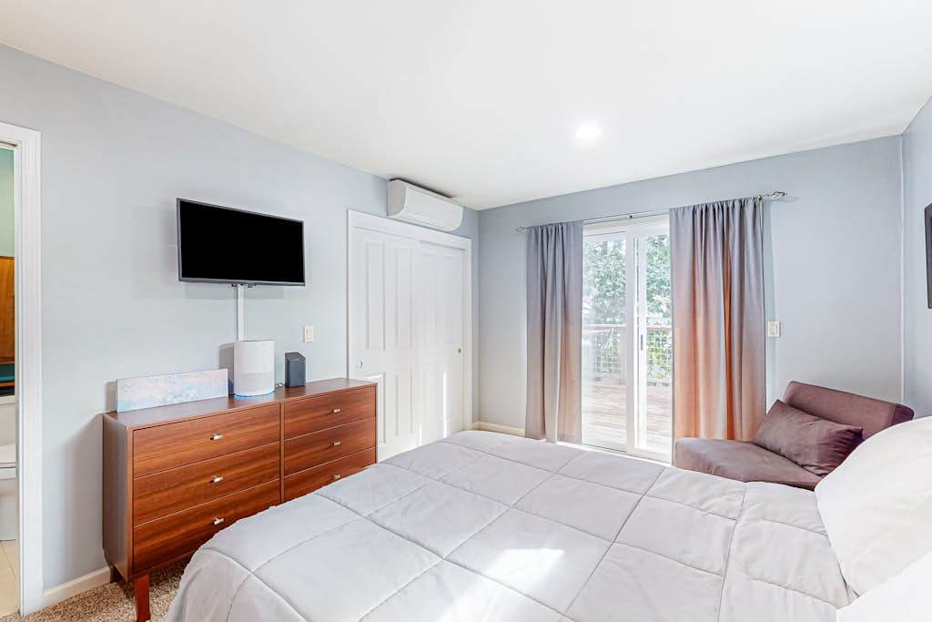 Your primary suite keeps you comfortable year-round with AC and a wall-mounted TV — step through the glass doors for morning coffee on the private deck.