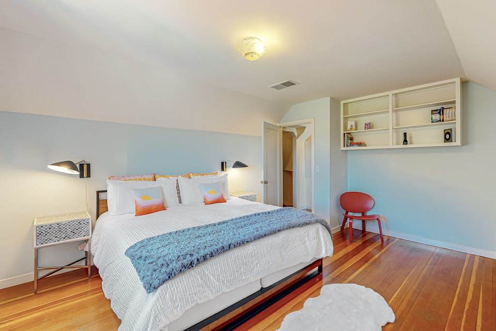 Drift off in crisp white linens with a cozy blue throw after a full day of Healdsburg adventures — bedside lamps and built-in shelves keep everything within reach.