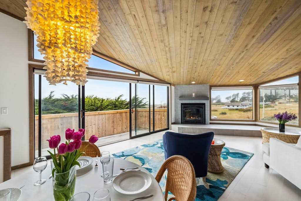 From candlelit dinners to lazy coastal mornings, your open great room connects kitchen, dining, and fireside lounging under one soaring roof