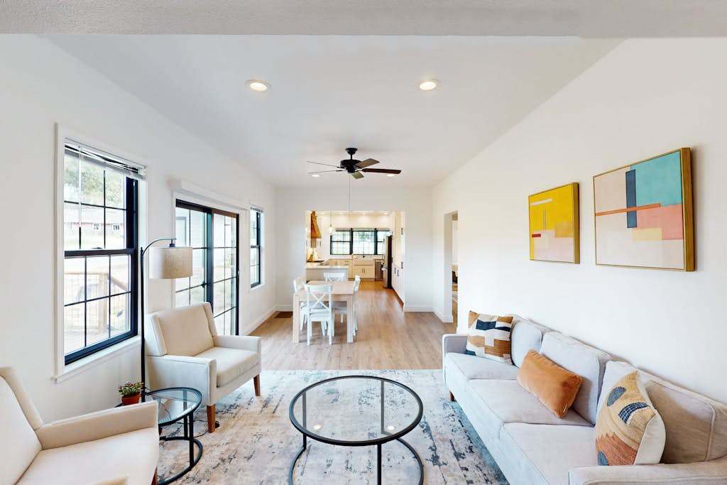 Unwind in your sun-drenched open-concept living space — plush seating, modern art, and hardwood floors flow seamlessly into the dining and chef's kitchen beyond.