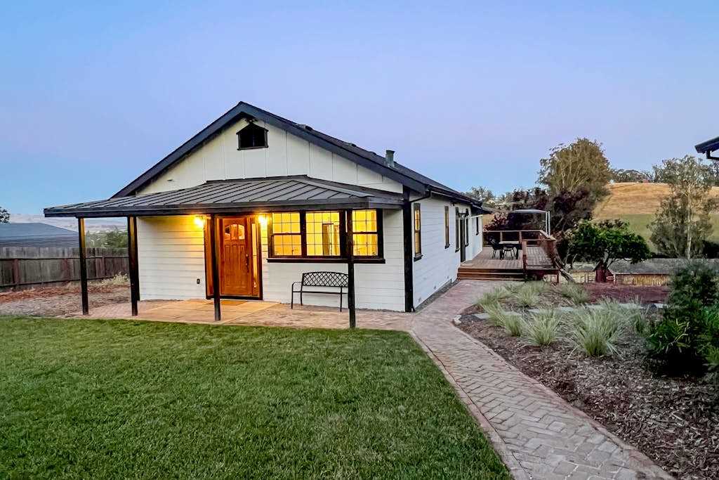Welcome to your modern farmhouse escape in Penngrove — warm interior light spills through black-framed windows as a brick path guides you to a beautifully renovated wine country retreat.