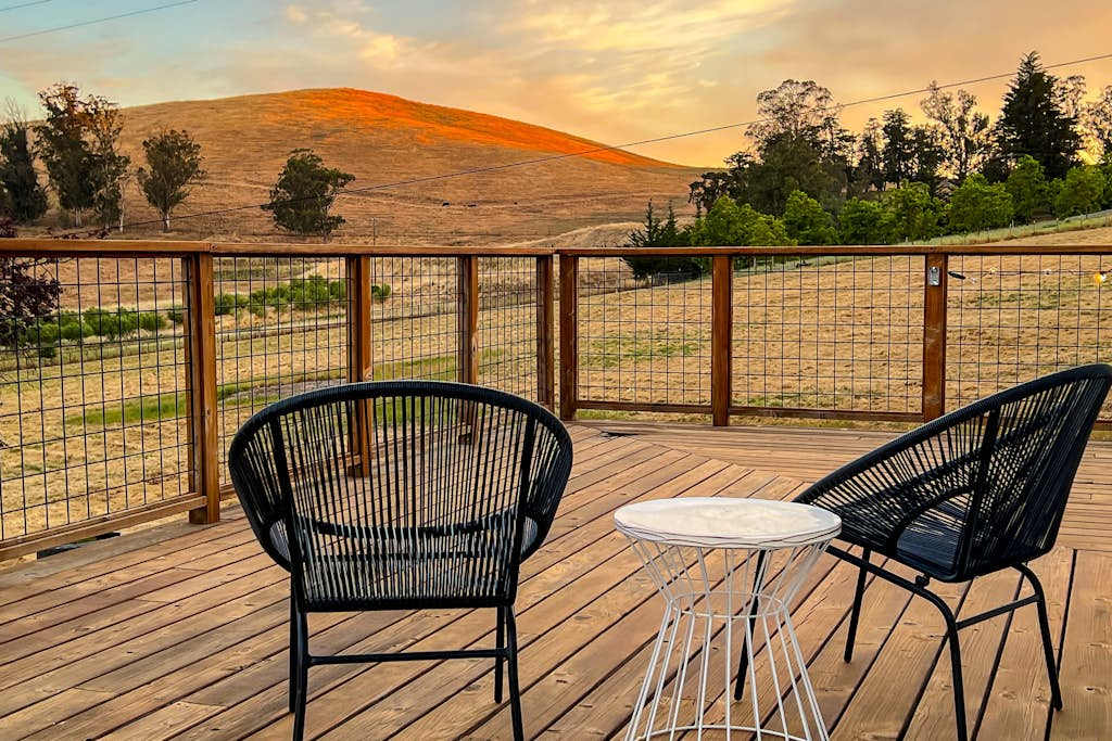 Settle into your private deck at golden hour — two modern chairs framing sweeping Sonoma Valley hill views, the perfect perch for sipping local Pinot after a day of wine tasting.