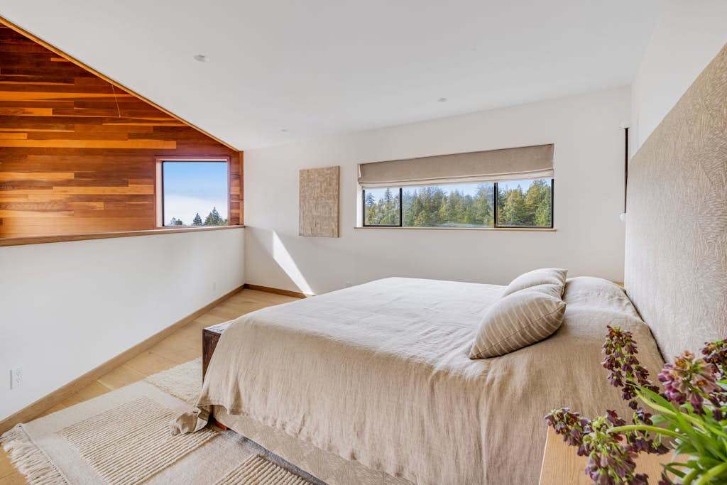 Morning light dances across this inviting master bedroom, offering a perfect escape for relaxation and rejuvenation in nature's embrace.