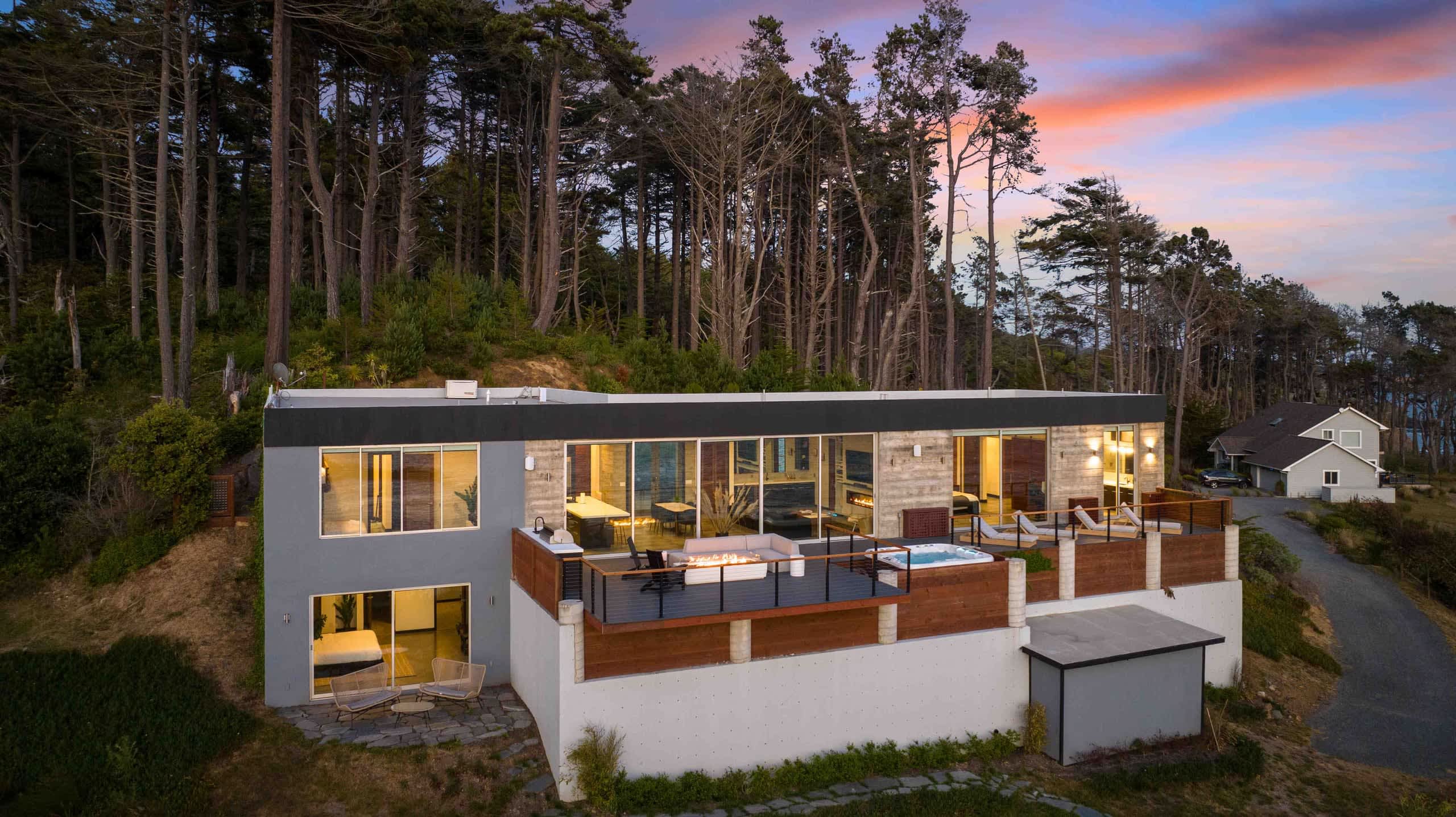 Sunset over the house and its full-length deck, with the forest closing in behind.