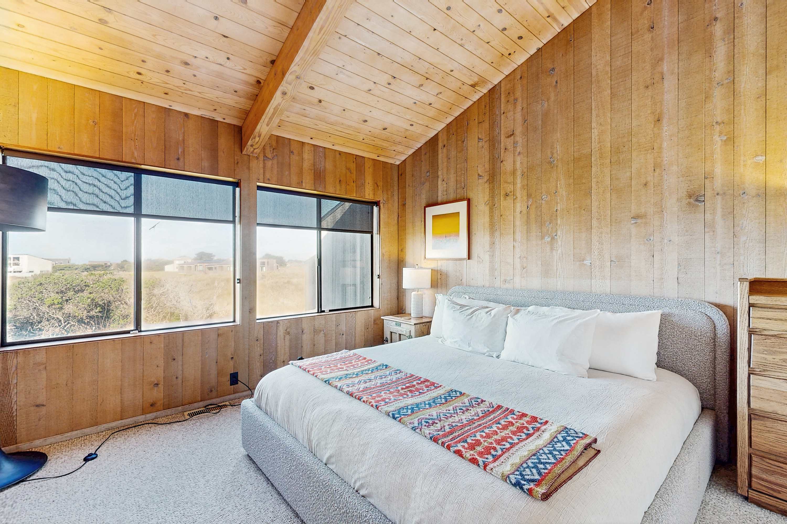 Wake up in the primary bedroom to meadow and ocean views through large windows -- the king bed and warm wood walls make it hard to leave.